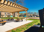 Thumbnail 10 of 52 - a grill in front of a park with picnic tables  at Bayville Apartments, Virginia Beach, 23455
