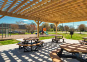 Thumbnail 11 of 52 - two picnic tables under a wooden pavilion in a park  at Bayville Apartments, Virginia Beach