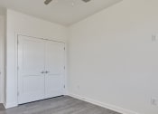 Thumbnail 39 of 47 - an empty bedroom with white doors and a door to a closet at The Port at East Beach Apartments and Marina, Norkfolk, VA, 23518