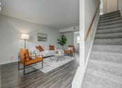 Thumbnail 8 of 32 - a living room with a staircase and a couch and chairs