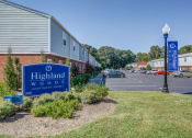Thumbnail 21 of 32 - a sign for highland woods apartments in front of a parking lot