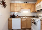 Thumbnail 10 of 28 - A kitchen with wooden cabinets and white appliances.