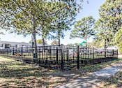 Thumbnail 3 of 22 - A black metal fence surrounds a grassy area with trees.