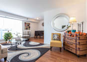 Thumbnail 8 of 22 - A living room with a yellow chair and a wooden chest of drawers.
