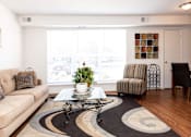 Thumbnail 7 of 22 - A living room with a couch, coffee table, and a striped chair.