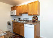 Thumbnail 11 of 22 - A kitchen with wooden cabinets and white appliances.