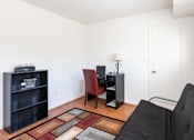 Thumbnail 16 of 22 - A living room with a black couch, a red chair, and a black bookshelf.