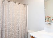 Thumbnail 14 of 19 - A shower curtain with a pattern is hanging in a bathroom.
