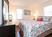 Thumbnail 12 of 19 - A bedroom with a floral bedspread and a framed picture on the wall.
