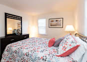 Thumbnail 11 of 19 - A bedroom with a floral bedspread and a large mirror on the dresser.
