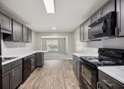 Thumbnail 47 of 57 - a kitchen with black appliances and white counter tops and wooden floors at Shellbrook, Raleigh, 27609