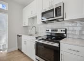 Thumbnail 11 of 47 - Discover the heart of home in our newly custom-built kitchens, complete with stainless steel appliances, quartz countertops, and ceramic tile backsplash at Centro at Pine Nash, Wilson, NC
