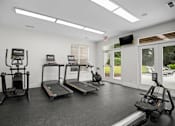 Thumbnail 17 of 29 - A spacious gym with treadmills, elliptical machines, and a television.
