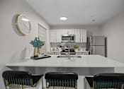 Thumbnail 1 of 29 - A kitchen with a white countertop and black chairs.