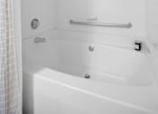 Thumbnail 8 of 29 - A white bathtub with a shower curtain on the left side.