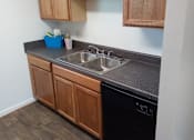 Thumbnail 4 of 20 - A kitchen with wooden cabinets and a black countertop.