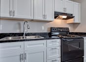 Thumbnail 1 of 31 - A modern kitchen with white cabinets and black countertops.