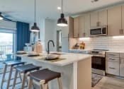 Thumbnail 7 of 38 - a kitchen with a large island and stools in front of a counter top at Aura Stonebridge, Richmond
