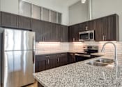 Thumbnail 67 of 88 - A kitchen with a granite countertop and stainless steel appliances.