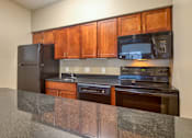 Thumbnail 8 of 33 - A kitchen with wooden cabinets and black appliances.