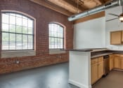 Thumbnail 13 of 46 - an empty kitchen with exposed brick walls and a ceiling fan at The Hudson, Virginia
