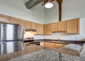 Thumbnail 9 of 46 - a kitchen with granite countertops and wooden cabinets at The Hudson, Richmond, VA, 23224