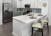Thumbnail 19 of 42 - A modern kitchen with a white island and two chairs.