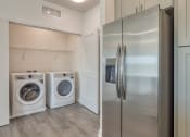 Thumbnail 40 of 47 - a laundry room with a washer and dryer and a stainless steel refrigerator at The Port at East Beach Apartments and Marina, Norkfolk, VA