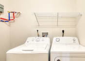Thumbnail 32 of 35 - two washers and a dryer in a laundry room with a shelf above them