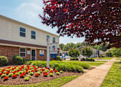 Thumbnail 25 of 26 - A building with a sign in front of it and a flower bed in the front.