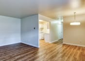 Thumbnail 16 of 24 - an empty living room with wood flooring and a renovated kitchen at Gates of West Bay in Norfolk, 23503