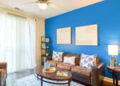 Thumbnail 36 of 60 - a living room with a blue wall and a couch and a table at Proximity at ODU, Norfolk, Virginia