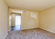 Thumbnail 13 of 26 - A large empty room with a carpeted floor and a doorway leading to another room.