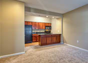 Thumbnail 7 of 33 - A kitchen with a black refrigerator and wooden cabinets.