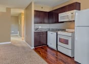 Thumbnail 11 of 33 - A kitchen with white appliances and brown cabinets.