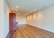 Thumbnail 26 of 35 - a living room with white walls and wood flooring and a sink