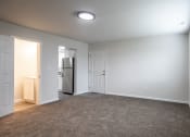 Thumbnail 3 of 36 - an empty living room with white walls and a door to the kitchen