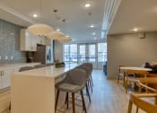 Thumbnail 38 of 42 - an open kitchen and dining area with a long counter and chairs at The Bella at Westchester, Virginia