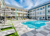 Thumbnail 16 of 33 - A large outdoor swimming pool surrounded by sun loungers and umbrellas.