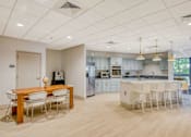 Thumbnail 20 of 33 - A kitchen with a dining table and chairs in the foreground and a kitchen in the background.