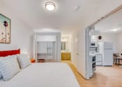 Thumbnail 5 of 33 - A bedroom with a bed, a fridge, and a table.