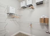 Thumbnail 16 of 56 - A white closet with clothes hangers and storage boxes.