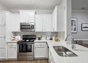 Thumbnail 2 of 56 - A modern kitchen with white cabinets and stainless steel appliances.