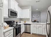 Thumbnail 1 of 56 - A kitchen with white cabinets and appliances.