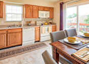Thumbnail 15 of 36 - A kitchen with wooden cabinets and a dining table with two chairs.