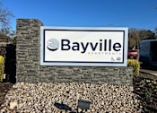 Thumbnail 1 of 52 - A property sign for Bayville Apartments is displayed in front of a stone wall.