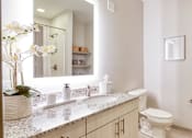 Thumbnail 37 of 40 - A bathroom with a toilet, sink, and a mirror.