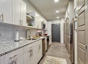 Thumbnail 23 of 40 - A kitchen with a granite counter top and stainless steel appliances.