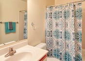 Thumbnail 25 of 36 - A bathroom with a white sink and a shower curtain with a blue and white pattern.