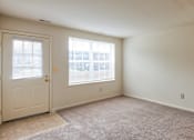 Thumbnail 18 of 36 - A room with a carpeted floor, a door, and a window with blinds.